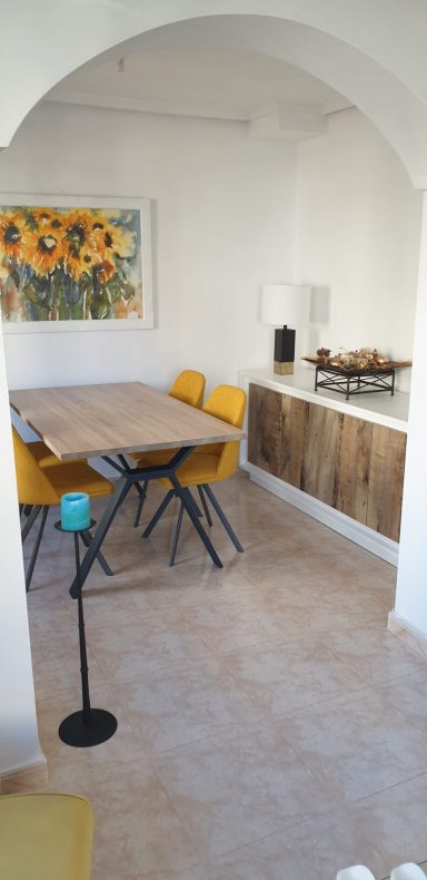 Eetkamer Eettafel met gele stoelen in lichte, moderne ruimte met zonnebloemen aan de muur.